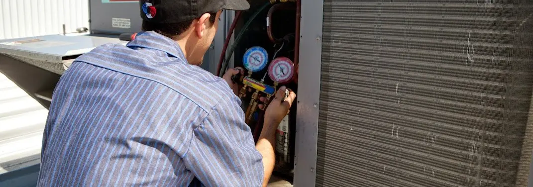 HVAC technician servicing a condenser unit in Loudon